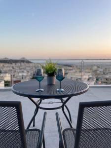 a table with two wine glasses on a balcony at Acropolis Panorama Studio in Athens