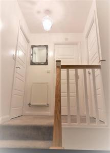 a white hallway with a staircase and a mirror at Beautiful 4 Bedroom Treasure home in Hemel Hempstead