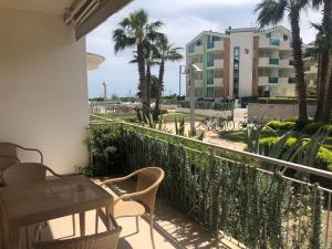 a balcony with a table and chairs and palm trees at Casa Del Mar in Roseto degli Abruzzi