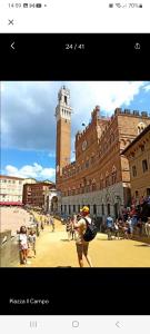 a man taking a picture of a building with a clock tower at La Bomboniera di Siena in Siena