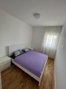 a bedroom with a purple bed and a window at Apartman Čapljina in Čapljina