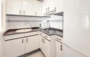 a white kitchen with a sink and a microwave at 1 Bedroom Nice Apartment In Cullera in Cullera