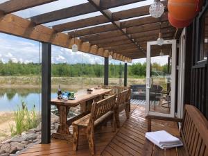 a wooden deck with a table and chairs and a lake at Brīvdienu māja Rozes in Šķēde