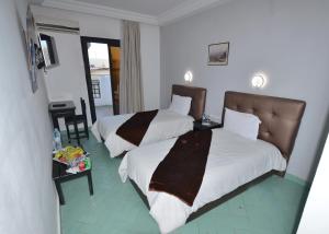 pokój hotelowy z 2 łóżkami i telewizorem w obiekcie Hotel Nouzha w Fezie
