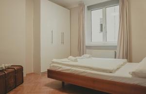 ウィーンにあるHeyMi Apartments Schwedenplatzのベッドルーム1室(白いシーツ付きのベッド1台、窓付)