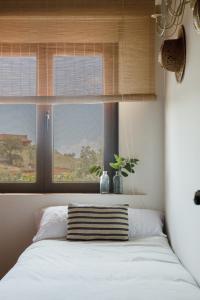 Dormitorio con cama con ventana y almohada en Casa Rural en Candeleda con piscina y un maravilloso jardín, en Candeleda