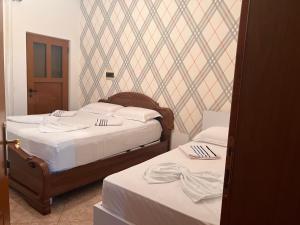 two beds in a bedroom with white sheets at Fori Vodo in Divjakë