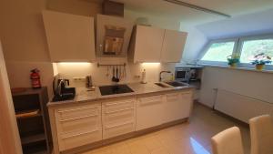 a kitchen with white cabinets and a sink at Lakeside Hills Apartment, Appartement in Krumpendorf am Wörthersee