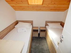 two beds in a small room with wooden ceilings at Aqualux apartments in Vrdnik