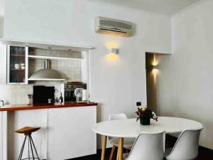 uma cozinha branca com uma mesa e cadeiras brancas em Magnifico appartamento quartiere Trieste/Africano em Roma