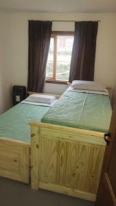 a bedroom with a wooden bed with a window at Hogar del Sur in Tolhuin