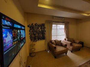 a living room with two couches and a flat screen tv at Private 1-Bedroom Apartment in Rawalpindi