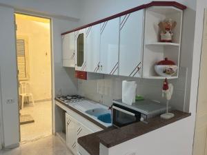 a kitchen with white cabinets and a sink and a microwave at Casa Giancontieri in Marinella di Selinunte