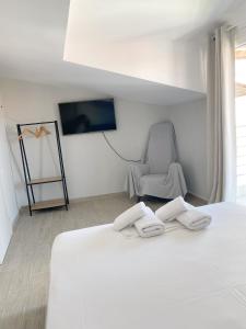 a bedroom with a white bed and a chair at Delia Apartments in Pefkohori
