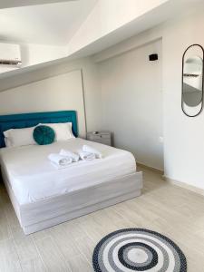 a bedroom with a large white bed with a blue headboard at Delia Apartments in Pefkohori