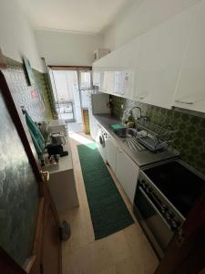 a kitchen with white cabinets and a green rug at Pilar Hostel - Rua de Santa Catarina - Porto in Porto
