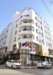 un bâtiment blanc avec deux voitures garées devant lui dans l'établissement Hotel Nouzha, à Fès