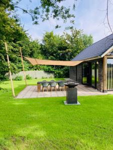 a patio with chairs and a table in a yard at Luxe schuurwoning 't Nieuwt in Chaam, Nederland in Chaam