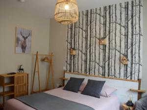 1 dormitorio con 1 cama y una pared con árboles en La Maison de Jeanne, en Capvern