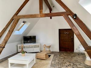 uma sala de estar no sótão com vigas de madeira e uma televisão em Hôtel Particulier de Champrond em Chartres