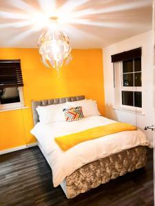 a bedroom with yellow walls and a bed with a chandelier at Beautiful 4 Bedroom Treasure home in Hemel Hempstead +37 photos