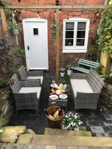 a patio with wicker chairs and a white door at Boutique style cottage Bridgnorth in Bridgnorth