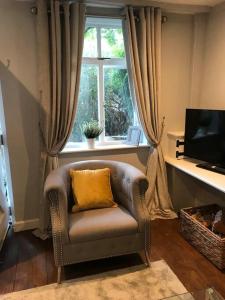 a chair with a yellow pillow sitting in front of a window at Boutique style cottage Bridgnorth in Bridgnorth