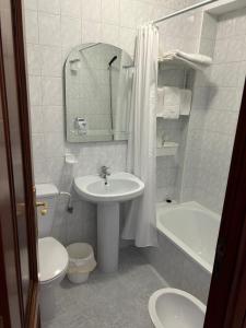 a bathroom with a sink and a toilet and a bath tub at Pensión Rey in Isla de Arosa