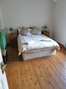 1 dormitorio con 1 cama, suelo de madera y 2 mesitas de noche en The Cobbler Rosscarbery Holiday Cottage, en Rosscarbery