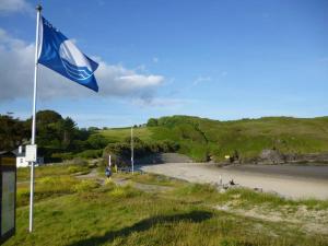 a blue flag on a pole next to a beach at The Cobbler Rosscarbery Holiday Cottage in Rosscarbery