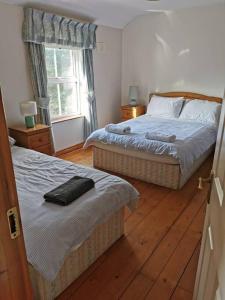 a bedroom with two beds and a window at The Cobbler Rosscarbery Holiday Cottage in Rosscarbery