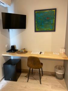 a desk with a chair and a monitor on a wall at Hôtel Les Vignes in Chassiers