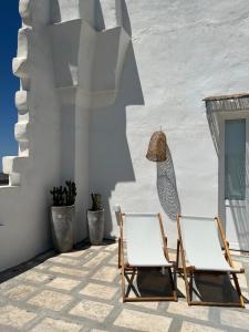 two chairs on a patio with a white wall at L’Edicola Votiva in Casarano