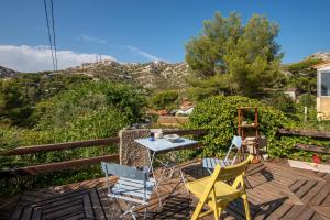 una mesa y sillas en una terraza con montañas al fondo en La Champanel Maison vue Mer JO24, en Marsella