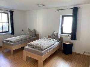 two beds in a room with two windows at Ferienwohnung sentio-comfortable Saalfeld in Saalfeld