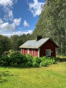 a small red house in a field with trees at Lappalaisen lomamökit Pihamökki in Puumala