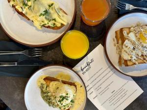 tre piatti di cibo con uova e pane tostato su un tavolo di BY14 TLV Hotel a Tel Aviv