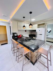 a kitchen with a large island with chairs in it at Ap Aquaville resort -CE in Aquiraz
