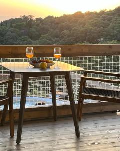a table with two glasses of wine on a balcony at Glamping - Il Giardino di San Giorgio in Montorgiali