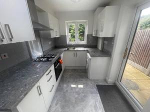 eine kleine Küche mit weißen Schränken und einem Fenster in der Unterkunft 5 Bed, easy access to Stratford/Central London in London