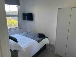 ein Schlafzimmer mit einem Bett und einem TV an der Wand in der Unterkunft 5 Bed, easy access to Stratford/Central London in London
