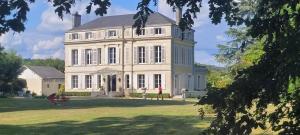 une grande maison blanche sur un champ herbeux dans l'établissement La maison au cèdre, à Marsac-sur-lʼIsle