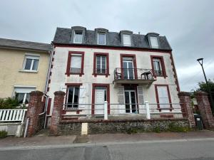 una antigua casa de ladrillo con balcón en una calle en Appartement F1, refait à neuf, 150m de la plage, en Donville-les-Bains