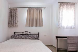 a bedroom with a bed and a desk and curtains at Anastasia's Apartment in Ioannina