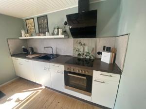 a kitchen with white cabinets and a stove top oven at Ferienhaus Glückszeit bei Goslar in Langelsheim