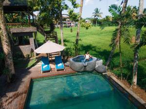 a person sitting in a chair next to a swimming pool at Uma Linggah Resort in Tampaksiring