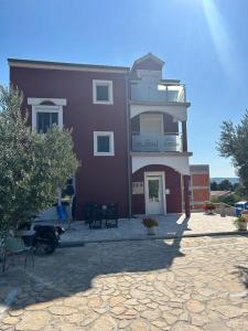 a large purple building with a porch and a patio at Villa Hercegovina in Sveti Filip i Jakov