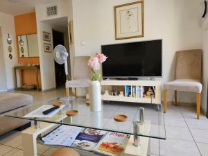 a living room with a tv and a glass table at Quiet & Comfortable Room in Raanana up to 1 guest in Shared Apartment in Ra‘ananna