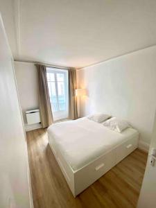 a white bedroom with a bed and a window at T2 Sacré Cœur - Butte Montmartre - Abbesses in Paris
