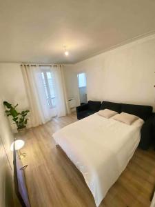 a bedroom with a large white bed and a couch at T2 Sacré Cœur - Butte Montmartre - Abbesses in Paris